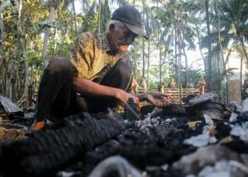 Kakek Arsyad memunguti yang tersisa dari rumahnya yang terbakar. Foto: Terkini ID