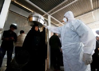 Tim medis memeriksa suhu penumpang di Lintas Perbatasan Shalamcha antara Irak dan Iran. Foto: Reuters